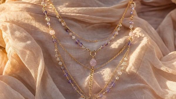 Layered crystal body chain with amethyst and rose quartz beads draped on flowing fabric